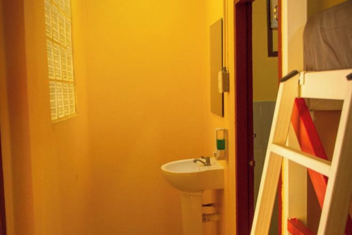 A bathroom with a white sink, a mirror, and a window with blinds.