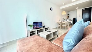 Een moderne woonkamer met een bank, televisie en een eethoek op de achtergrond.