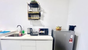 Een kleine keuken met een spoelbak, koffiezetapparaat, magnetron en koelkast.