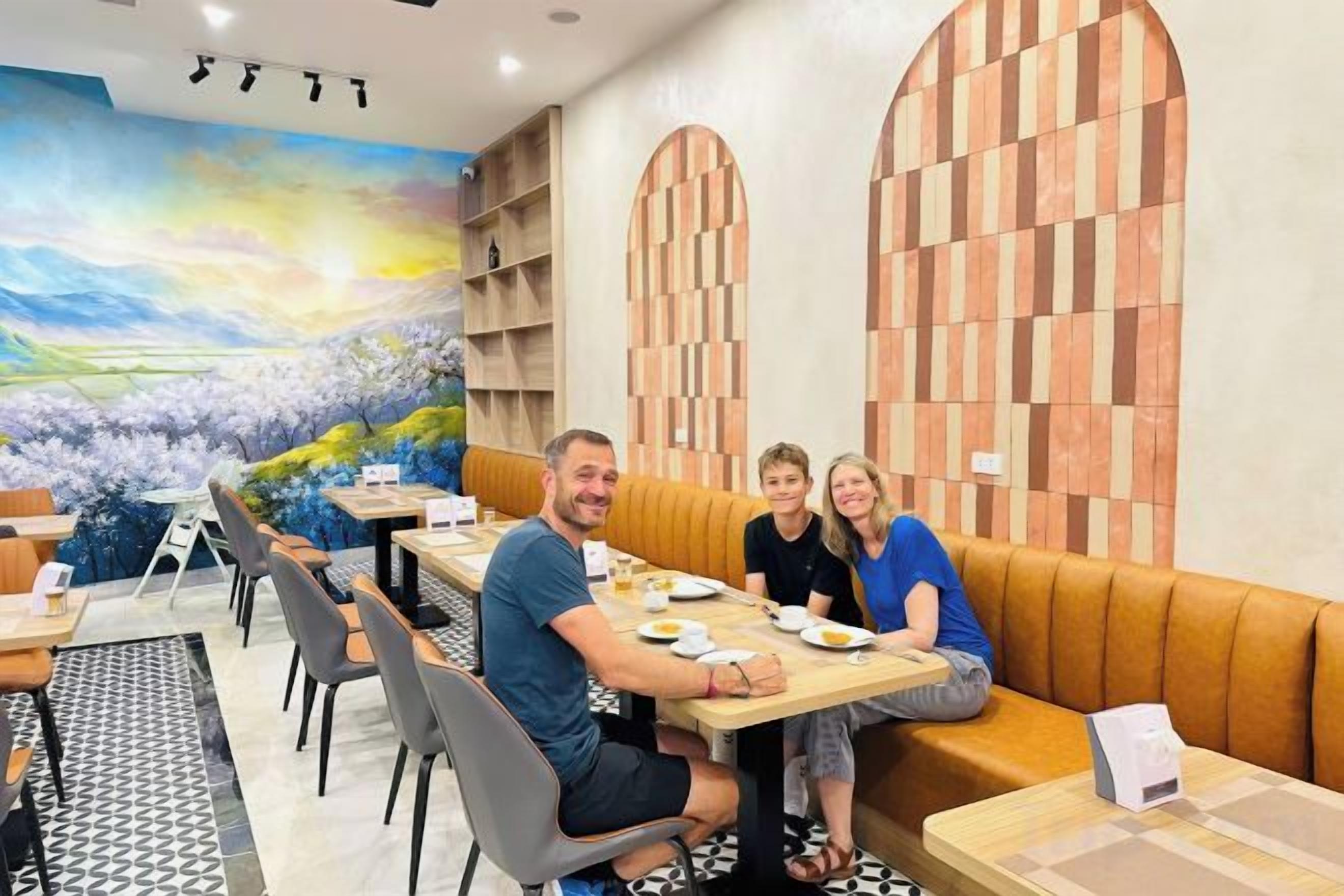 A restaurant with a mural, wooden panel wall, and a seating area with tables and chairs.