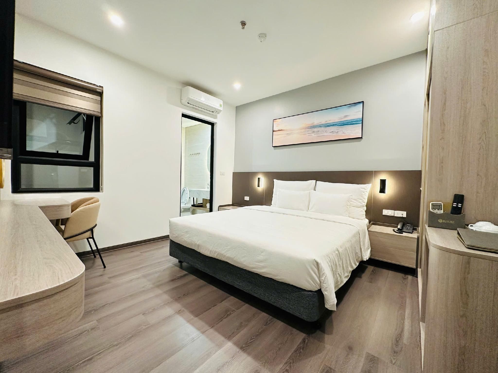 A modern hotel room with a large bed, a desk, and a chair.