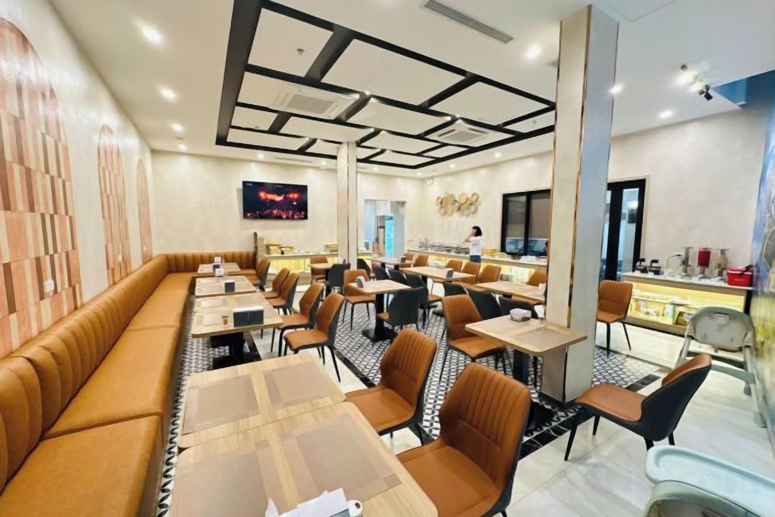 A modern restaurant with long communal tables, individual booths, and a bar area.