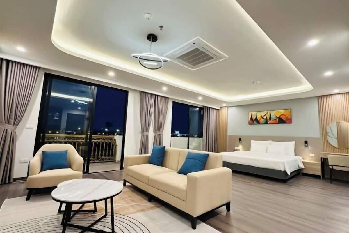 Ein modernes Hotelzimmer mit einem großen Bett, einem Sofa, einem kleinen Tisch und einem Balkon mit Vorhängen.