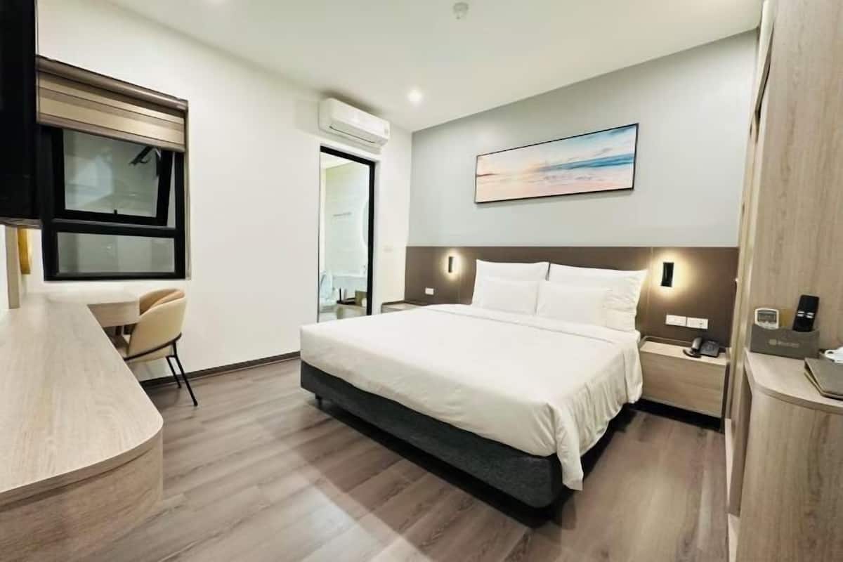 Ein modernes Hotelzimmer mit einem großen Bett, Nachttischen, einem Schreibtisch und einem Fenster.