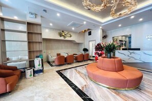 A hotel lobby with a reception desk, seating area, and a large chandelier. - BLUE SKY NOI BAI HOTEL & POOL (Hanoi)