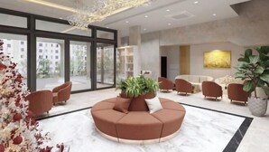 A modern lobby with a circular seating area, large windows, and a chandelier.