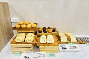 Une variété de produits de boulangerie présentés sur des plateaux en bois, notamment des pâtisseries et des muffins, chacun étant accompagné d’une étiquette indiquant son nom.