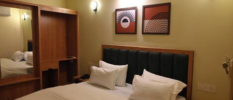 A hotel room with a large bed, a wooden headboard, a nightstand, a mirror, and two wall-mounted light fixtures.