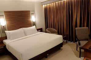 A hotel room with a large bed, two chairs, a wooden headboard, and a curtain. - Lume’os Hotel (Central Jakarta)