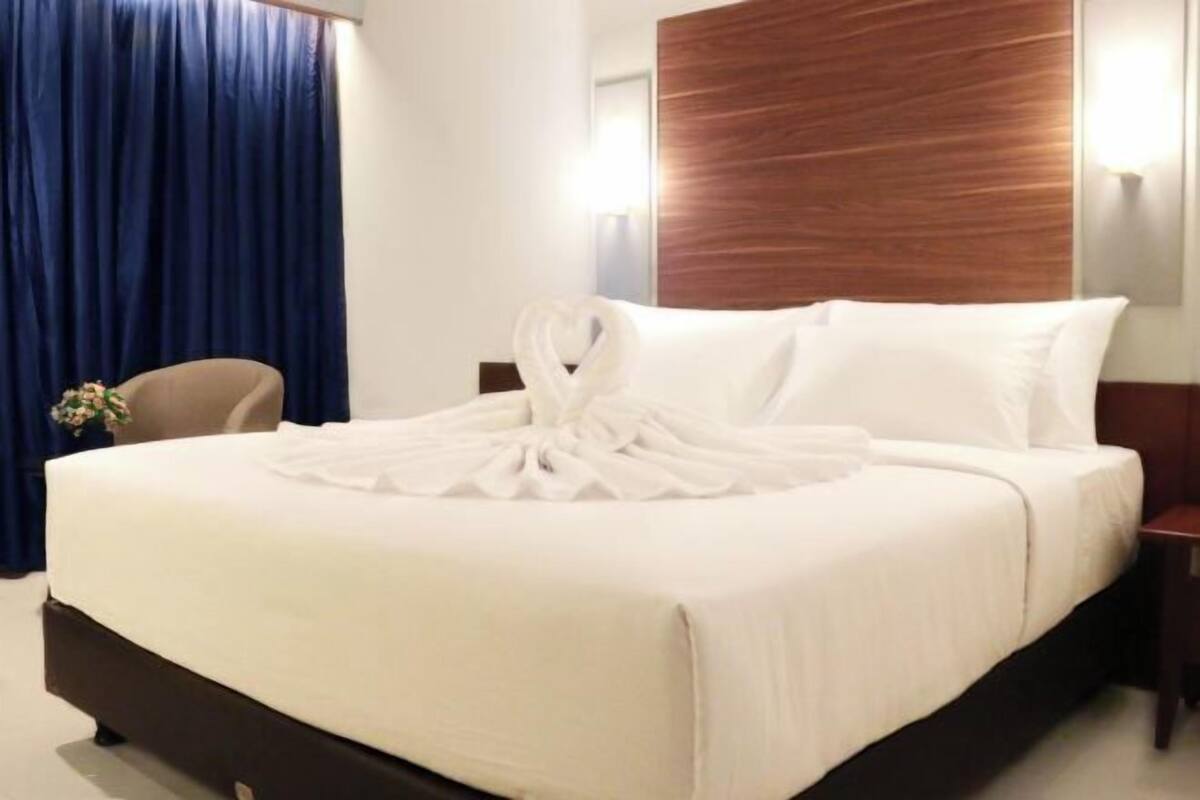 A hotel room with a bed, a wooden headboard, a nightstand, and a chair.