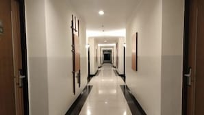 A long, narrow hallway with doors on both sides, leading to a darkened area at the end. - Lume’os Hotel (Central Jakarta)