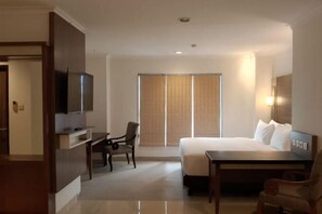 A hotel room with a bed, a desk, a chair, a television, and a sliding door. - Lume’os Hotel (Central Jakarta)