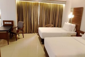 A hotel room with two beds, a desk, a chair, and a curtain. - Lume’os Hotel (Central Jakarta)