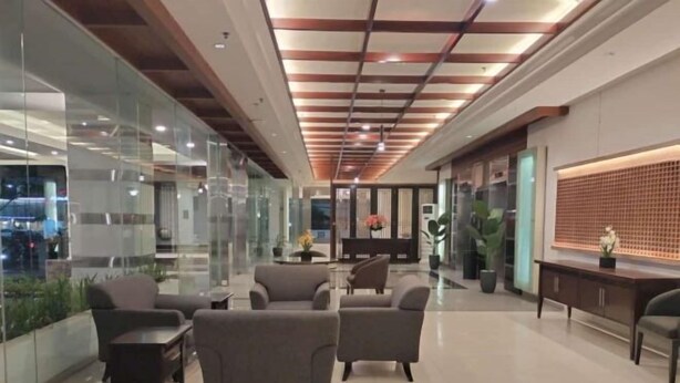 A modern lobby with glass walls, a reception desk, and seating area. - Lume’os Hotel (Central Jakarta)
