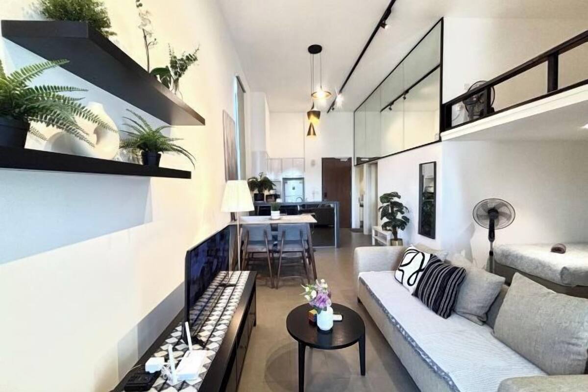 Una sala de estar moderna con un sofá, una mesa de centro y estanterías con plantas.