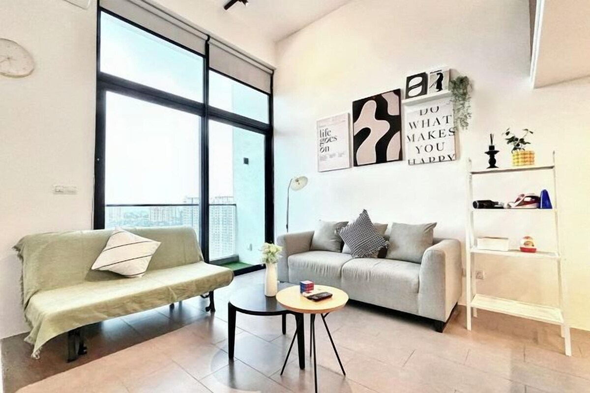 A modern living room with two sofas, a small round table, and a white shelving unit.