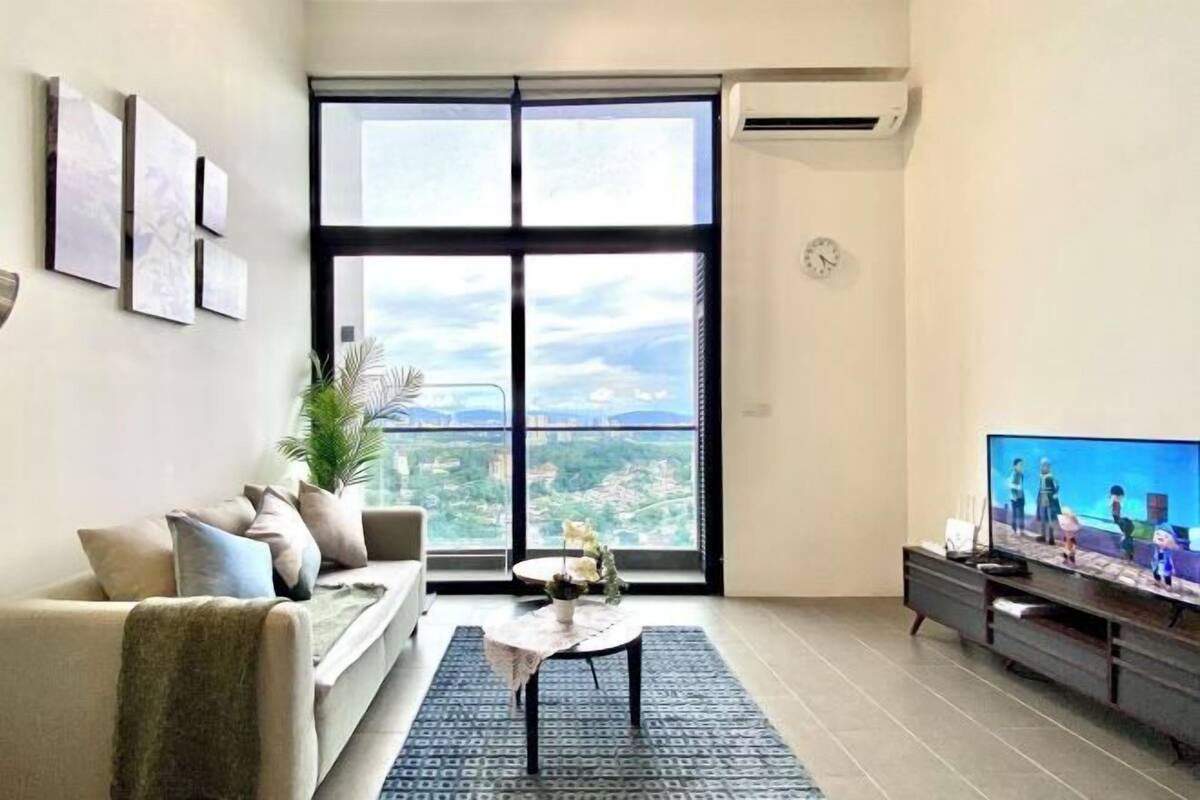 Una sala de estar moderna con un ventanal grande, un sofá, una mesa de centro y un televisor de pantalla plana.