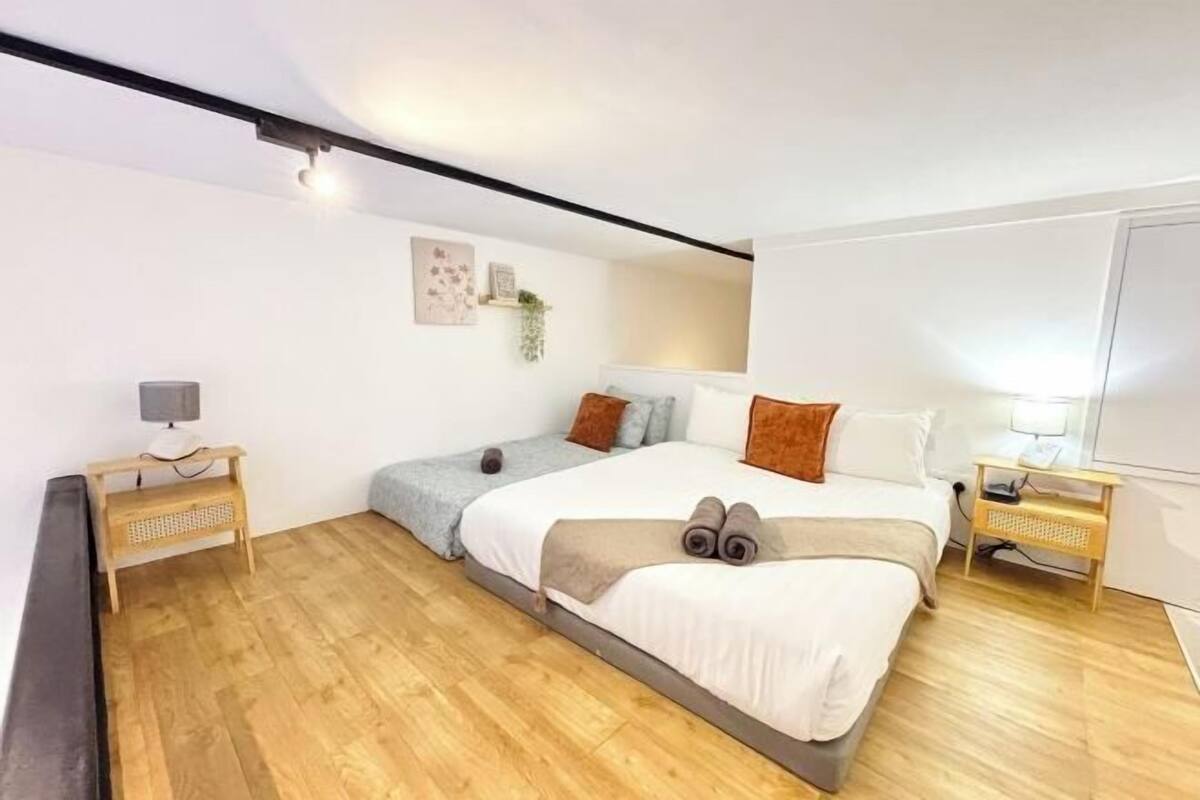 Un dormitorio con cama, mesitas de noche, lámpara y estante en la pared.