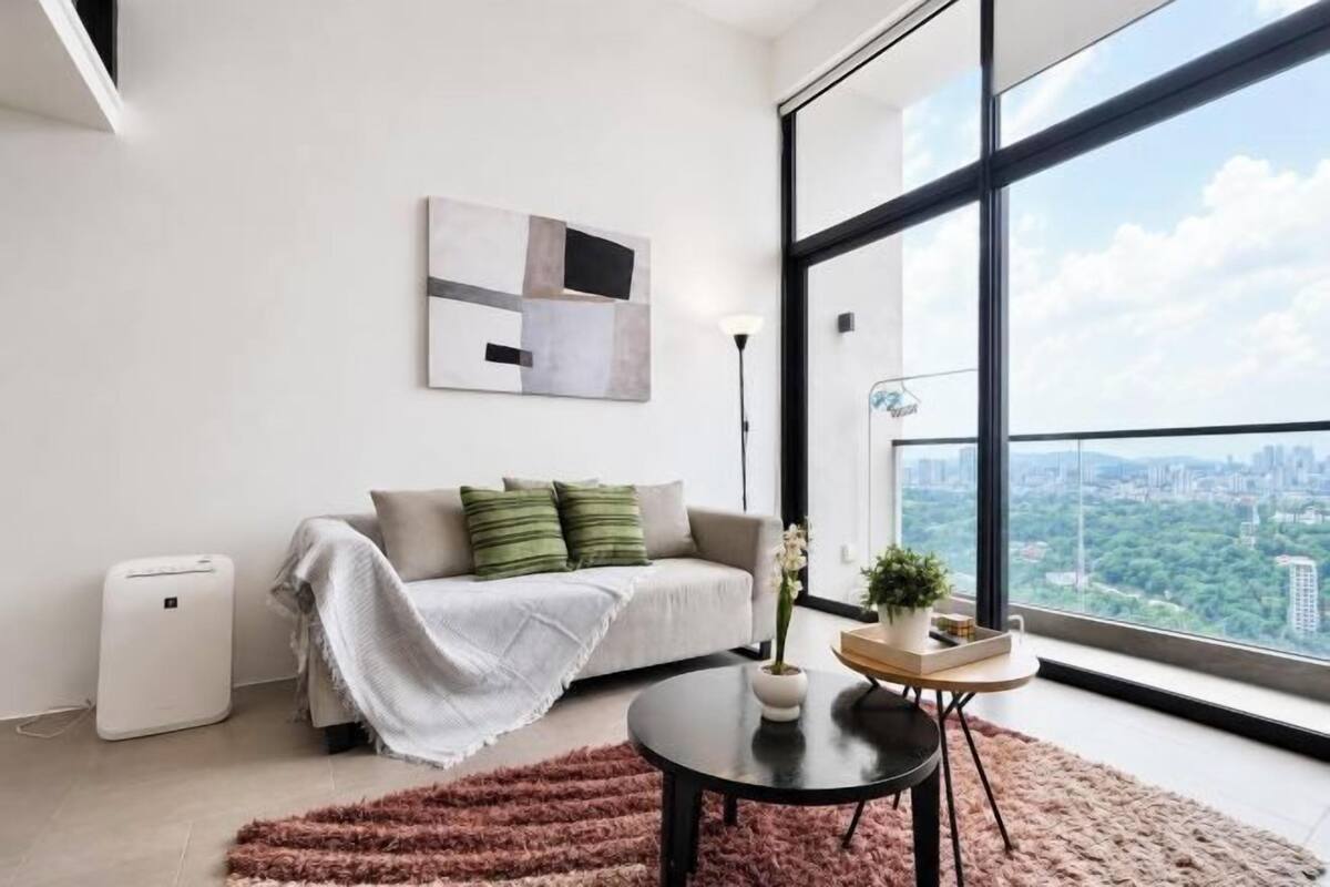 Una sala de estar moderna con un sofá, una mesa de centro, una planta en maceta y un ventanal con vistas a la ciudad.