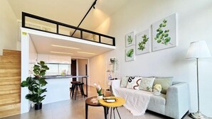 Un salon moderne avec un canapé, une table basse, une lampe et des œuvres d’art accrochées au mur.