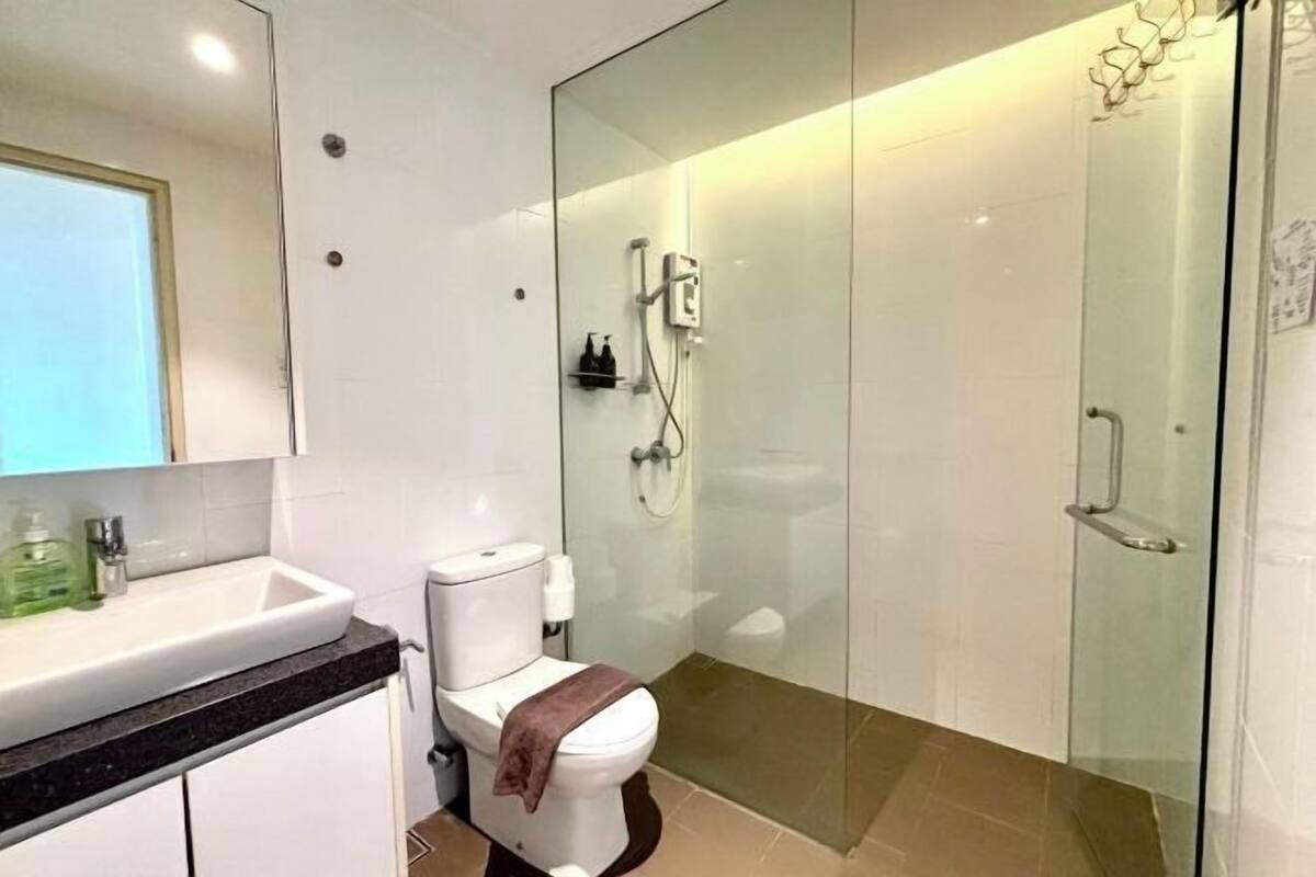 Un baño moderno con cabina de ducha de vidrio, inodoro blanco y lavabo con encimera de mármol.