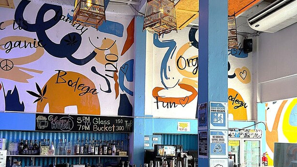 Un espace bar comprenant un comptoir, des sièges et une fresque murale avec du texte et des illustrations.