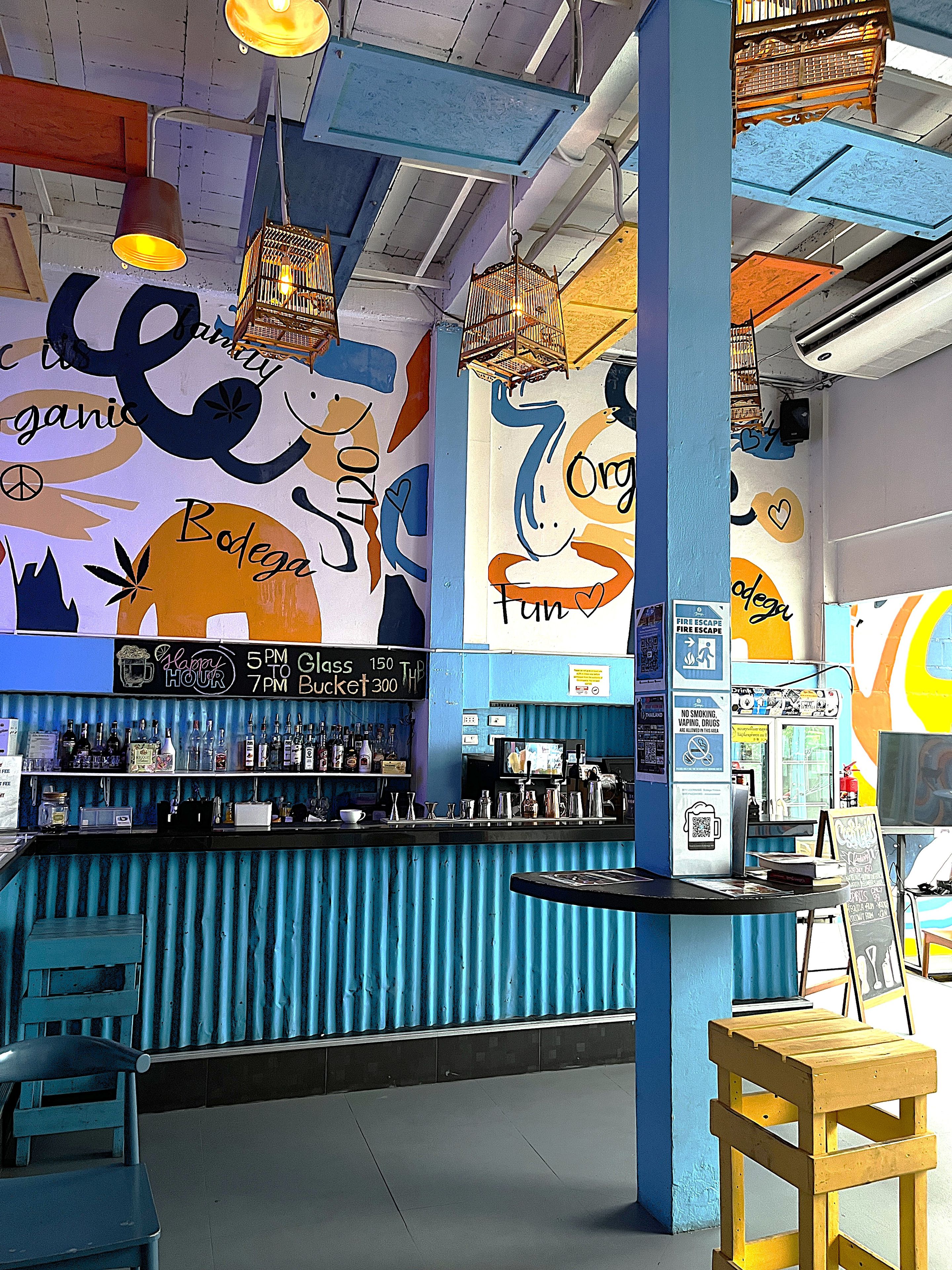 Zona de bar con mostrador, asientos y un mural con texto e imágenes.