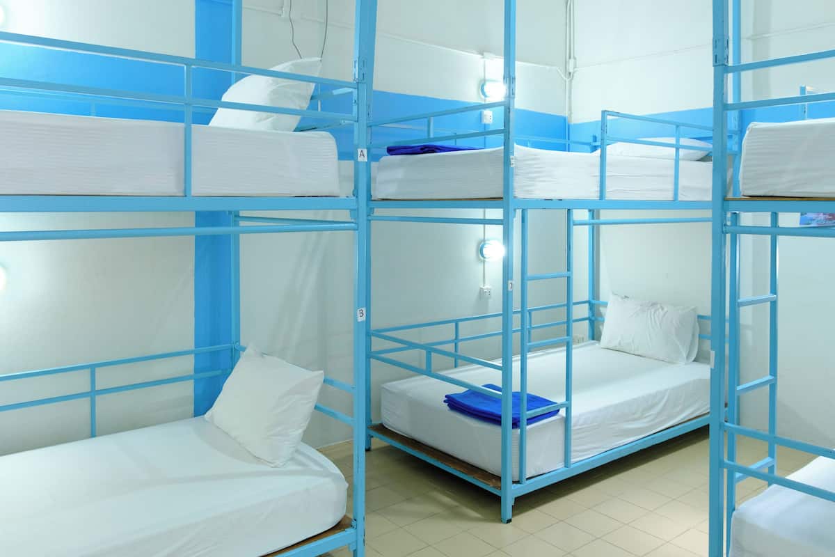 A bunk room with multiple beds, each with white bedding and blue railings.