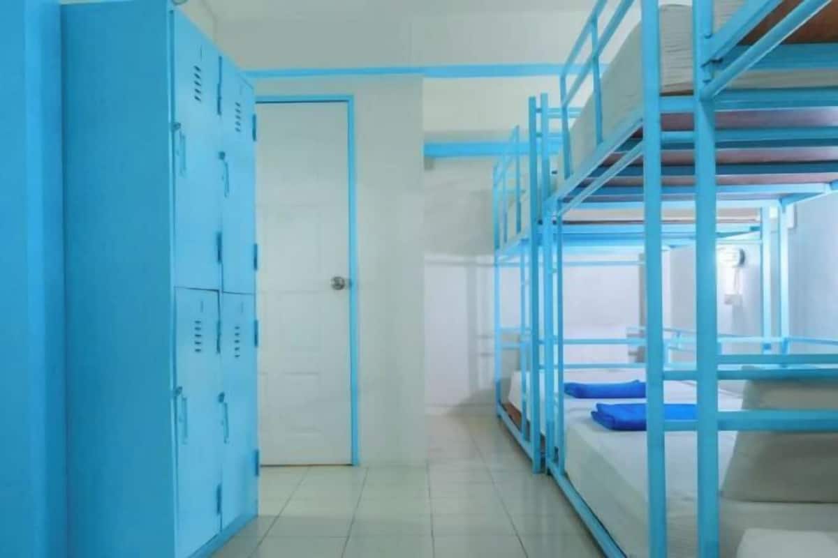 A corridor with bunk beds, lockers, and a door.