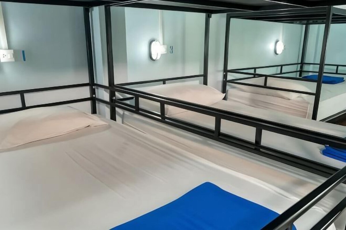 Habitación con literas, un espejo en la pared, un interruptor de luz y un enchufe.