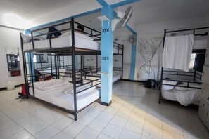 Ein Schlafsaalzimmer mit Etagenbetten, Zimmernummer 324, einem Ventilator und einem Wandbild.