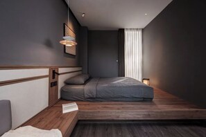 Un dormitorio moderno con diseño minimalista, que incluye una cama, una mesita de noche y una lámpara de noche pequeña.