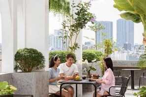 Un grupo de personas sentadas en una mesa al aire libre con vista a un paisaje urbano.