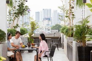 Terraza en la azotea con vistas a la ciudad, mobiliario exterior y plantas en macetas.