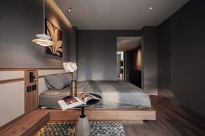Un dormitorio moderno con cama, mesita de noche, lámpara y una obra de arte en la pared.