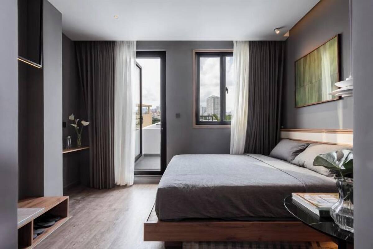 A modern hotel room with a large bed, a city view, and a minimalist design.