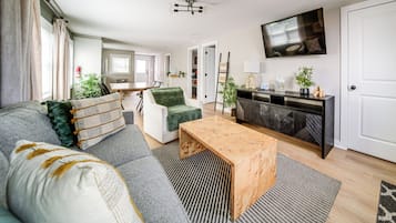 A modern living room with a sofa, coffee table, and a TV mounted on the wall.