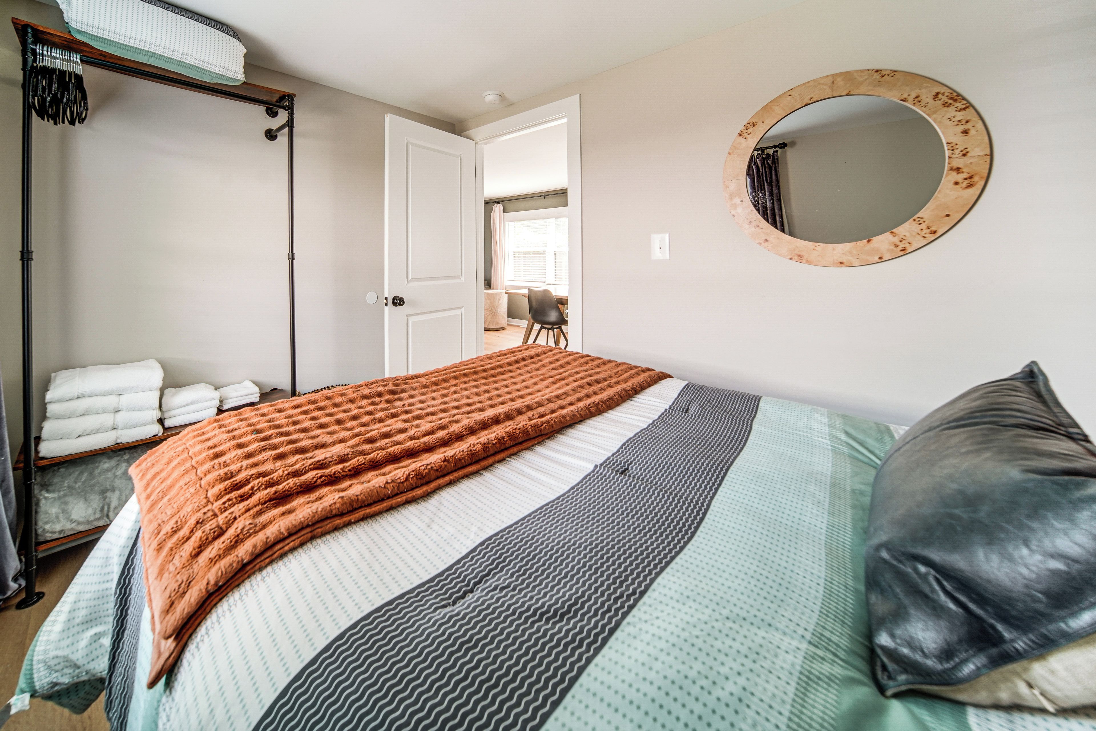 Un dormitorio con cama, espejo, armario y puerta que da a otra habitación.