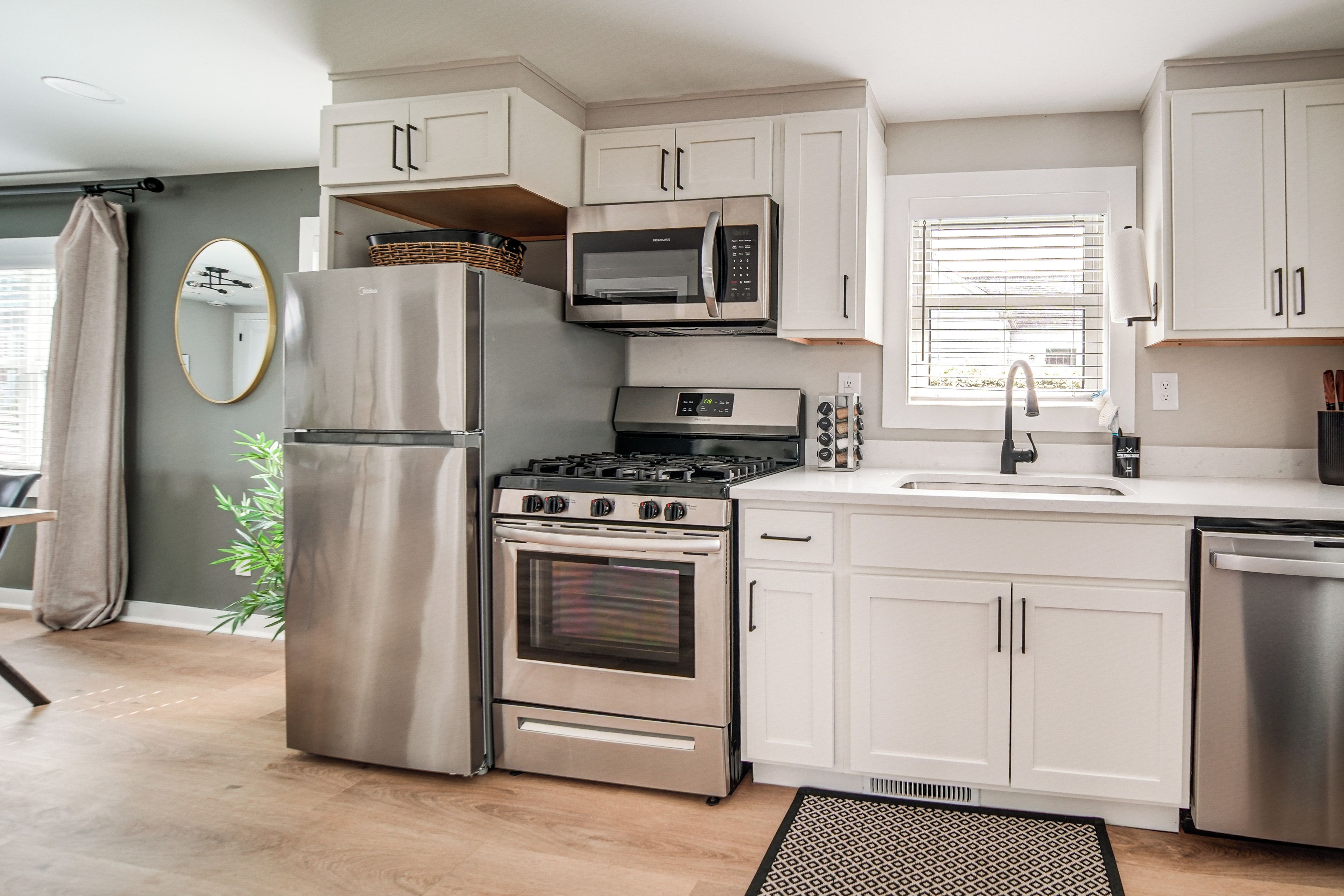A modern kitchen with stainless steel appliances, white cabinetry, and a built-in microwave.