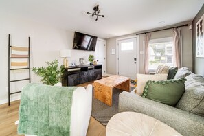 Una sala moderna con sofá, mesa de centro, televisor y una planta.