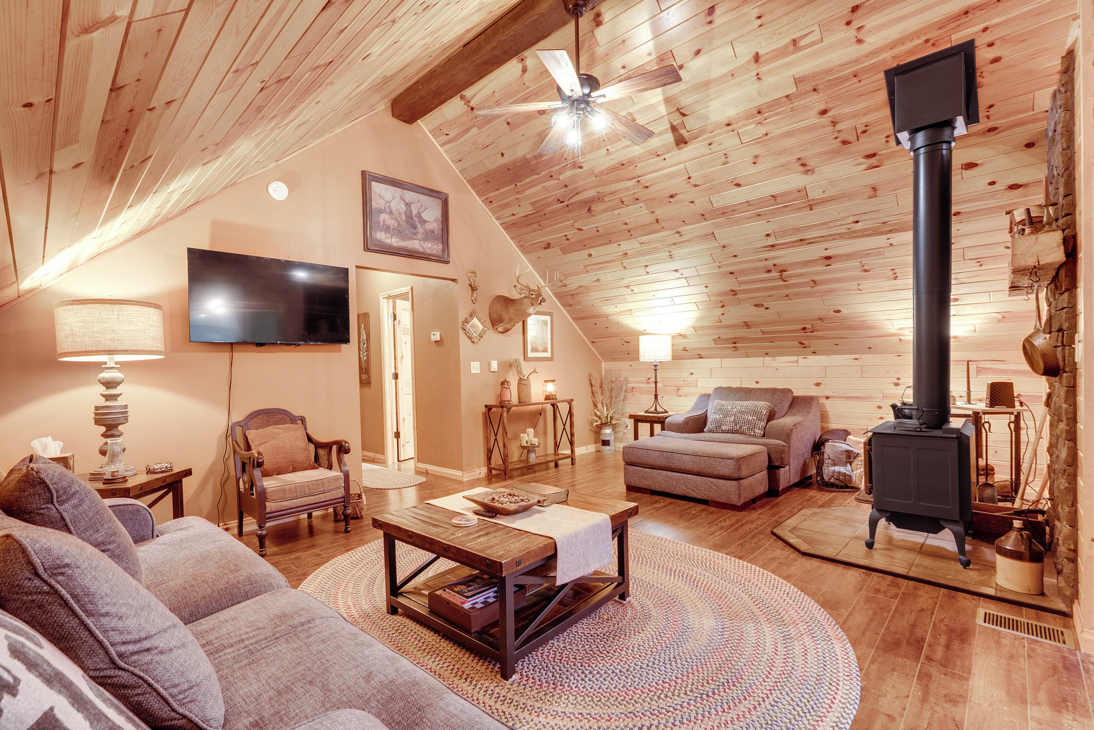 Un salon chaleureux, décoré avec des meubles en bois, doté d’une cheminée, d’un téléviseur et de sièges confortables.