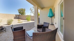 Una veranda coperta con mobili in vimini e una porta vetrata che si apre su un giardino.