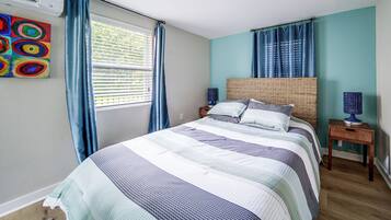 A bedroom with a bed, a nightstand, a lamp, and a window with curtains.