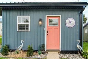 A house with a pink door, two windows, a welcome sign, and two bird sculptures. - 'Blue Heron' Walk to Kelso Beach! Pet-Friendly Gem (Erie)