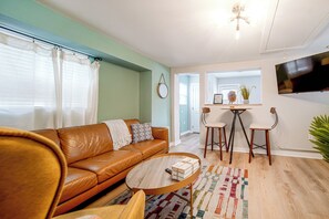 A living room with a brown leather sofa, a round wooden coffee table, and a colorful rug. - 'Blue Heron' Walk to Kelso Beach! Pet-Friendly Gem (Erie)