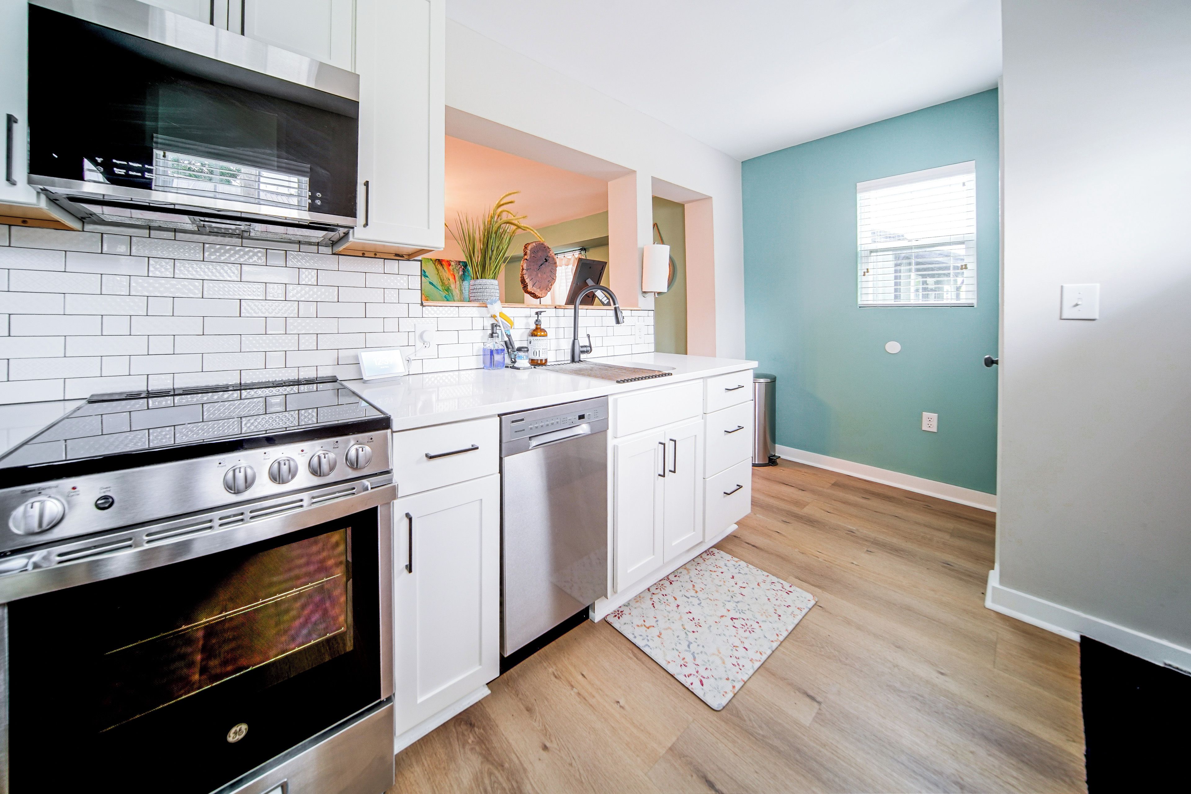 A modern kitchen with a built-in oven, a dishwasher, and white cabinetry.