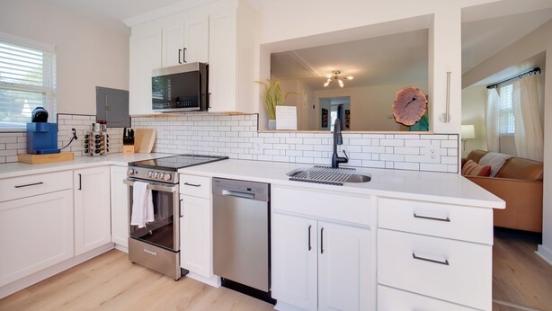 A modern kitchen with white cabinetry, a built-in oven, a dishwasher, and a microwave. - 'Blue Heron' Walk to Kelso Beach! Pet-Friendly Gem (Erie)
