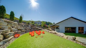 A well-maintained grassy area with stone walls and a building with a large garage door. - ‘Choo Choo Blue,’ Converted Railcar in DuBois! (DuBois)