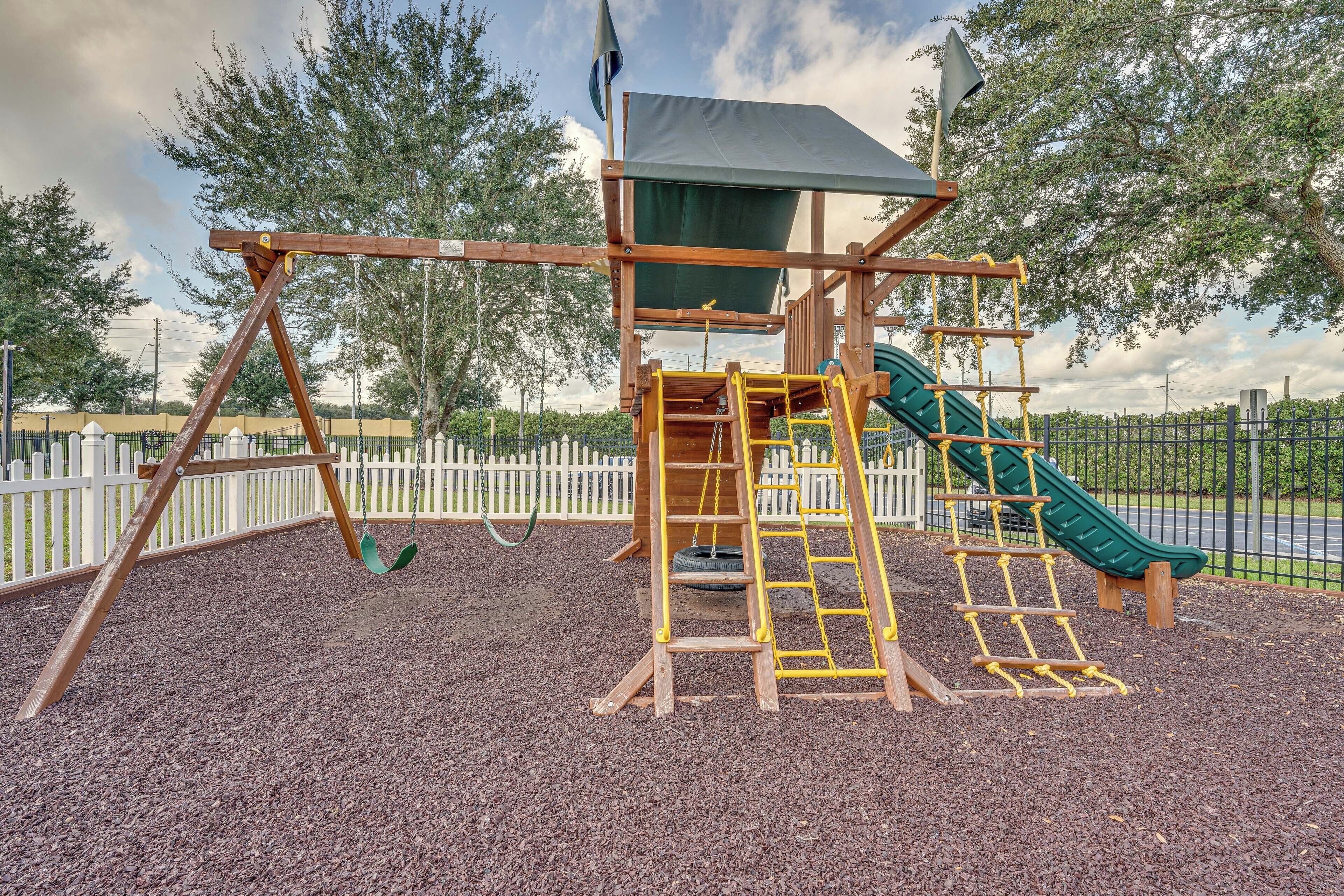 Une aire de jeux avec des balançoires, un toboggan et une structure d’escalade.