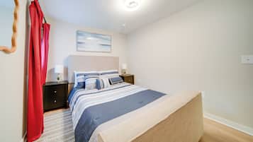 A bedroom with a bed, nightstands, a lamp, a painting, and a red curtain.